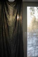 rideau sur fenêtre. aube à l'extérieur de la fenêtre. tissu à la lumière. photo