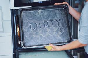 jeune femme nettoyant le four dans la cuisine photo