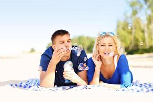 couple heureux faisant des bulles à la plage photo