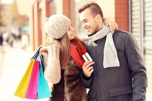 jeune couple avec carte de crédit shopping dans la ville photo