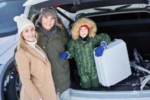 jeune famille pendant le voyage d'hiver dans le coffre de la voiture photo