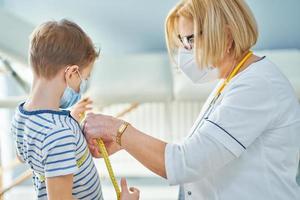 médecin pédiatre examinant les petits enfants en clinique ruban à mesurer photo