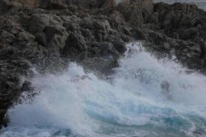 mer atteignant les rochers créant des éclaboussures d'écume photo