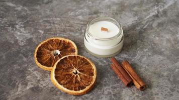 bougie faite à la main avec mèche en bois dans un bocal en verre avec de la cannelle et des oranges sèches photo