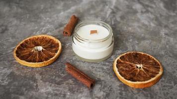 bougie faite à la main avec mèche en bois dans un bocal en verre avec de la cannelle et des oranges sèches photo