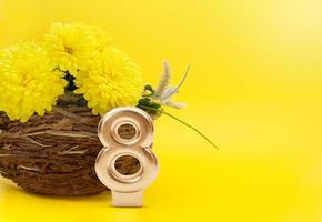 bouquet de chrysanthèmes dans un vase en jute et numéro 8 sur fond jaune. cadeau pour la journée internationale de la femme, 8 mars, anniversaire. copie espace photo