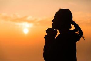 concept chrétien adorer ou prier dieu. silhouette de femme chrétienne avec amour, foi, dévotion à dieu avec fond de ciel de lever de soleil. adorer Dieu pour la paix, la victoire, le succès avec espoir. religion photo