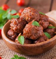 boulettes de viande à la sauce tomate aigre-douce et basilic dans un bol en bois photo