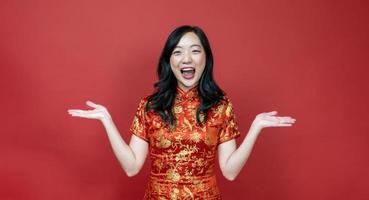 femme chinoise asiatique avec cheongsam rouge ou qipao excitant et riant pour souhaiter la bonne chance et la prospérité dans les vacances de célébration du nouvel an chinois isolées sur le concept de fond rouge photo