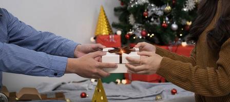 femme heureuse donnant une boîte-cadeau de noël et du nouvel an à une femme à la maison.célébration de noël en famille. décoration de Noël. relation amoureuse photo