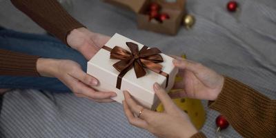 femme heureuse donnant une boîte-cadeau de noël et du nouvel an à une femme à la maison.célébration de noël en famille. décoration de Noël. relation amoureuse photo