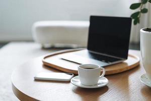 lieu de travail avec une tasse de café, ordinateur portable ouvert sur une table en bois dans la salle de bureau, intérieur d'affaires photo