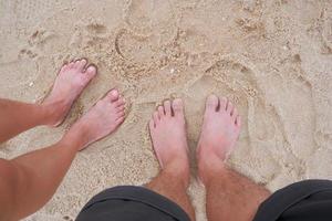 pieds d'un couple homme et femme debout sur une plage de sable. photo