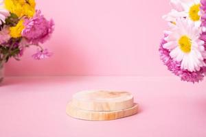 podium ou piédestal en bois avec fleurs de chrysanthème sur fond rose. maquette pour vos produits cosmétiques photo