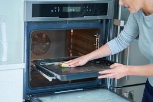 jeune femme nettoyant le four dans la cuisine photo