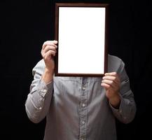 un diplôme vierge ou un certificat de maquette dans la main d'un employé portant une chemise sur fond noir. le cadre vertical de l'image est vide et l'espace de copie. photo