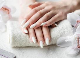 mains d'une jeune femme avec une manucure blanche sur les ongles photo