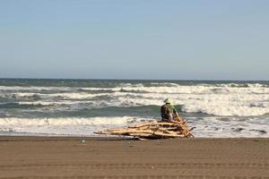 un vieil homme pêcheur assis et pêchant au bord de la mer photo