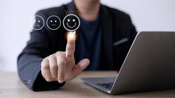 concept d'évaluation du service client. l'utilisation d'un smartphone appuie sur l'émoticône du visage souriant de satisfaction sur l'écran tactile virtuel. photo
