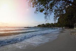 incroyable plage tropicale de sable avec silhouette pont en bois hors de la plage promenade tropicale ou passerelle en bois à l'horizon sur la mer océan paysage paradisiaque, lever ou coucher de soleil mer ciel dramatique photo