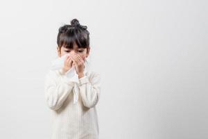 enfant asiatique fille malade avec des éternuements sur le nez et une toux froide sur du papier de soie parce que faible ou virus et bactéries du temps de la poussière photo