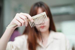 une femme asiatique a un problème avec la perte de cheveux longs attachée à la brosse à peigne. photo