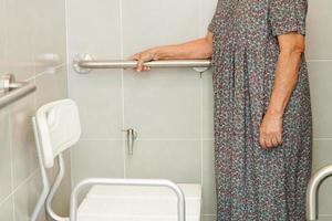 une vieille femme asiatique âgée utilise un rail de support de toilette dans la salle de bain, une barre d'appui de sécurité pour main courante, la sécurité dans l'hôpital de soins infirmiers. photo