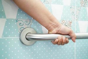 une patiente asiatique utilise le rail de support des toilettes dans la salle de bain, la barre d'appui de sécurité de la main courante, la sécurité dans l'hôpital de soins infirmiers. photo