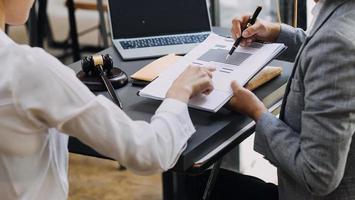 concept de justice et de droit. juge masculin dans une salle d'audience avec le marteau, travaillant avec, clavier d'ordinateur et d'accueil, lunettes, sur table à la lumière du matin photo