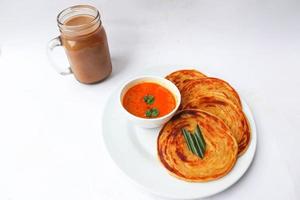 roti canai et teh tarik. pain paratha ou pain canai ou roti maryam, plat préféré du petit-déjeuner. servi sur assiette photo