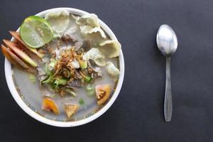 sop kaki kambing un aliment traditionnel de betawi, jakarta indonésie, à base de mouton ou d'agneau, d'abats, d'épices. isolé sur fond noir.cette nourriture est comme un ragoût d'agneau sur fond noir photo