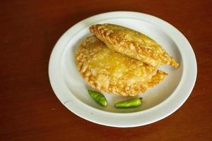 gâteau pastie ou gâteau pâtissier ou pastel kue servi avec du piment vert dans une petite assiette sur fond de bois. gâteau pastel indonésien photo