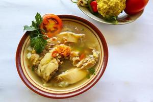 soupe au poulet servie avec légumes, tomates, céleri dans un bol, cuillère et fourchette. avec fond noir photo