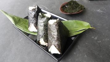 l'onigiri est la nourriture japonaise, la boule de riz japonaise, le triangle de riz aux algues, le nori isolé sur fond blanc photo