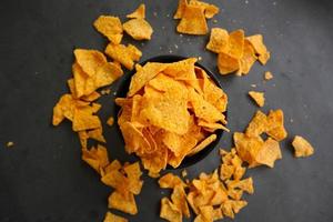 tortilla chips est des croustilles de maïs ou appelez des nachos, servis dans un bol, sur fond noir à base de maïs photo