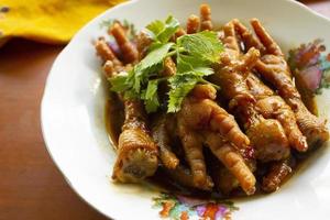 pieds de poulet épicés avec céleri, piment, oignon, ail servis avec une assiette blanche isolée d'un fond noir. photo