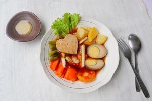 selat solo est une salade traditionnelle d'indonésie. à base d'œufs durs, de pois chiches bouillis, de carottes bouillies, de pommes de terre rissolées et de laitue, de steak ou de bistik. servi sur table en bois photo