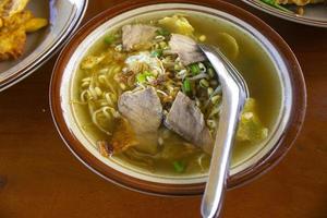 soto sapi. boeuf soto de la cuisine traditionnelle indonésienne de boyolali dans un bol blanc et fond de table en bois noir photo