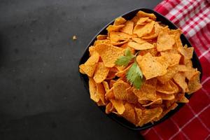 tortilla chips est des croustilles de maïs ou appelez des nachos, servis dans un bol, sur fond noir à base de maïs photo