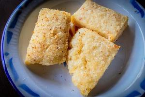 jadah goreng ou gâteau de riz gluant frit servi sur plaque émaillée. sur fond de bois photo