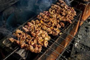 sate klatak ou sate kambing ou satay satay de chèvre, d'agneau, d'agneau ou de viande de chèvre avec un ingrédient de charbon de bois sur des grillades au feu rouge par des gens, indonésie cuisine satay. avec mise au point sélective photo