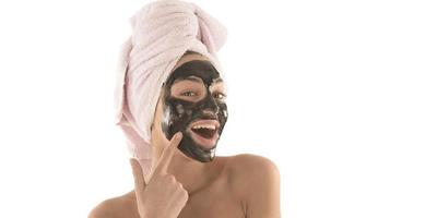 belle fille avec un masque cosmétique facial noir. notion de beauté. isolée photo