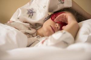 femme fatiguée dormant dans son lit portant un masque de sommeil avec les yeux bandés photo