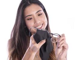 portrait d'une belle femme asiatique nettoyant ses lunettes isolées sur blanc photo