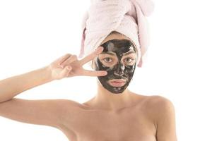 belle fille avec un masque cosmétique facial noir. notion de beauté. isolée photo