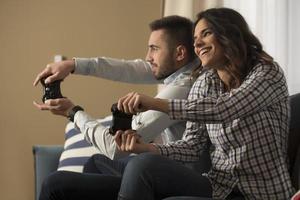 heureux couple souriant jouant à des jeux vidéo à la maison. photo