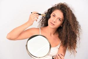 belle jeune femme souriante se maquiller avec un pinceau. isolée photo