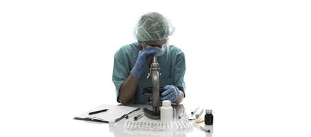 scientifique en gants médicaux bleus et uniforme d'apprentissage des échantillons de covid-19 avec microscope en laboratoire. photo