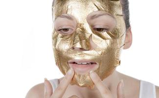 procédure cosmétique, le visage de la femme avec masque d'or sur fond blanc photo