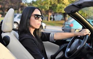 Heureuse belle femme au volant d'une voiture décapotable sport dans la ville photo